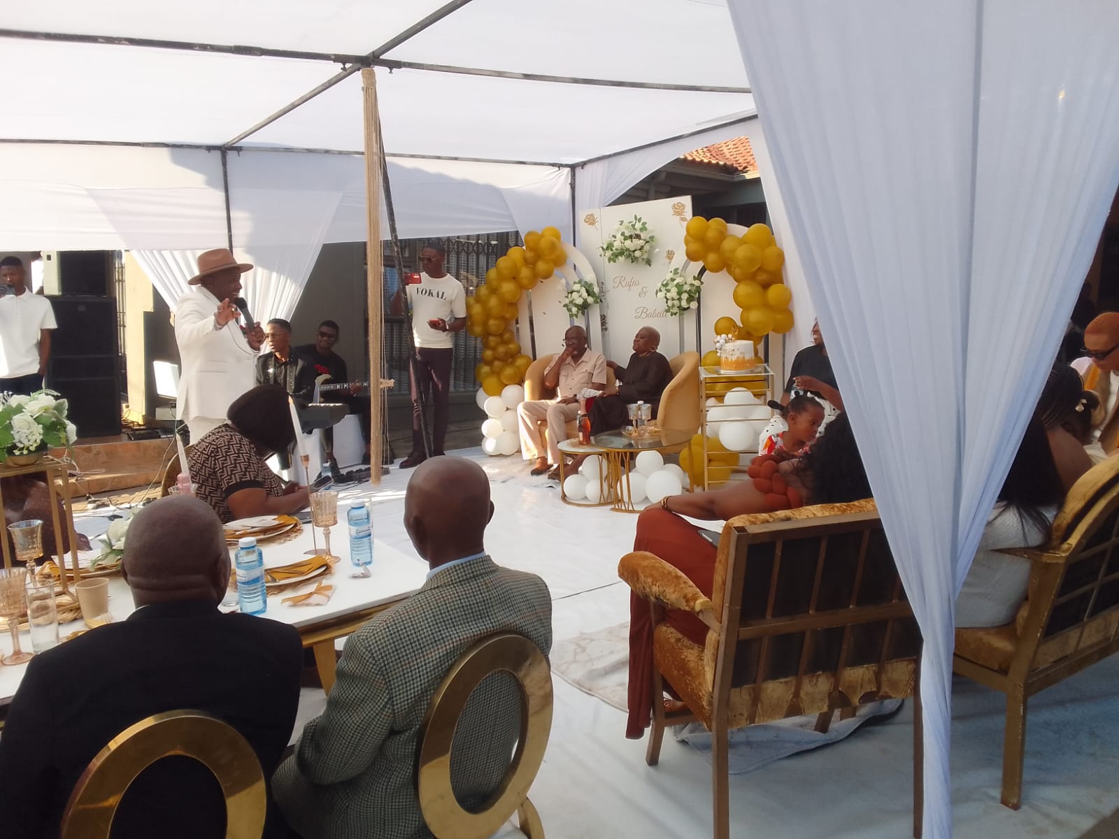 Outdoor event under a marquee with gold balloon decor