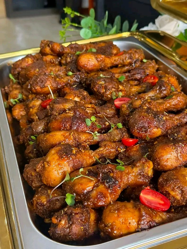 Tray of basted chicken drumsticks garnished with herbs