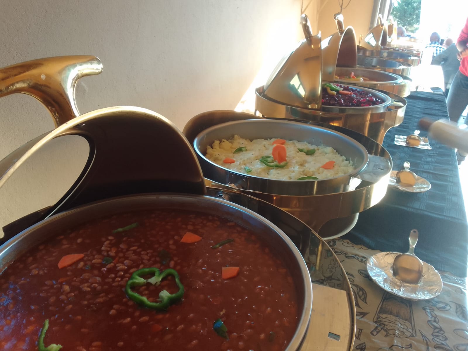 Buffet line with chafing dishes of beans, rice and salads