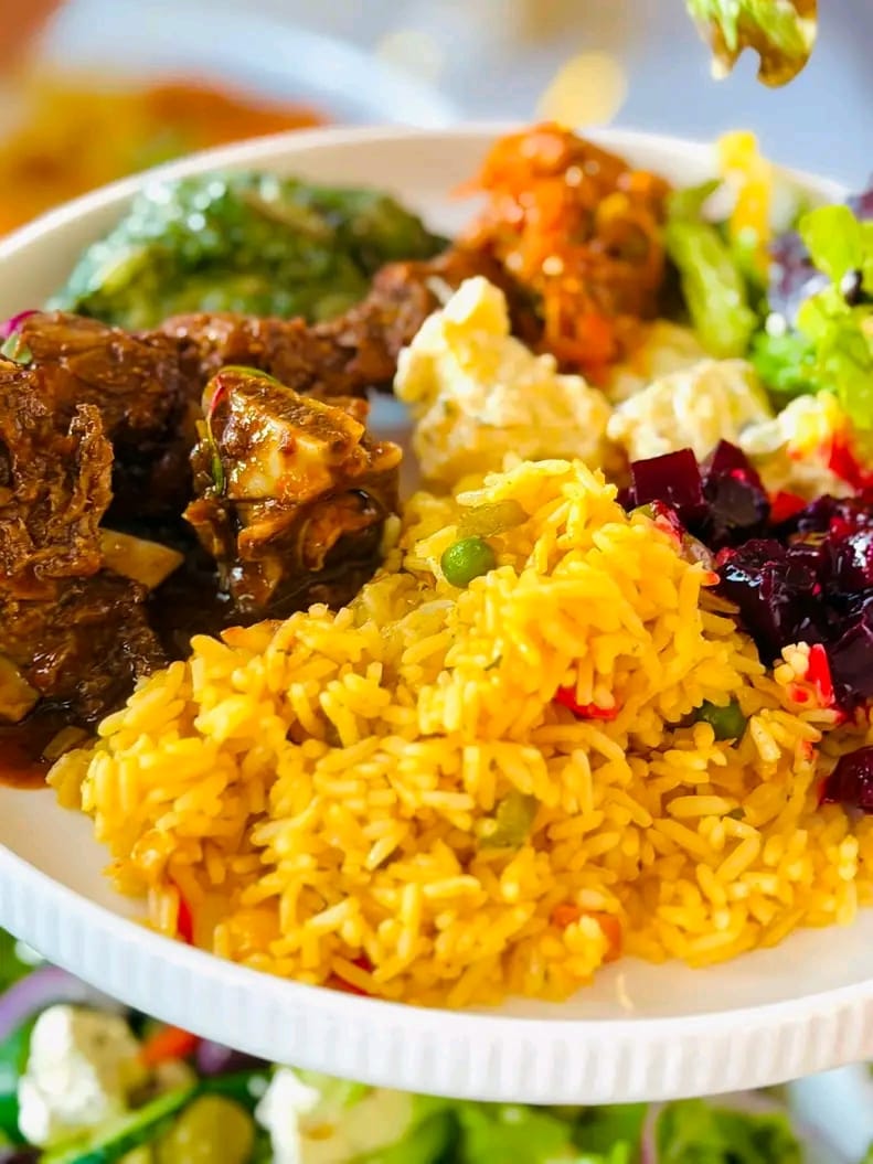 Plated yellow rice, beef stew, salads and beetroot from a Power Lady Services buffet